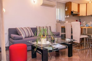 A modern living room with a sofa, a glass coffee table, and a red ottoman. - Apartment Karmen (Moscenicka Draga)