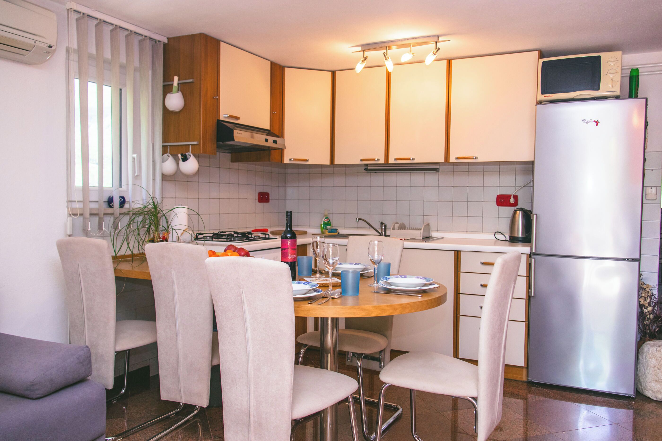 A kitchen with a dining table, chairs, a refrigerator, and a microwave.
