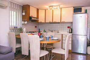 A kitchen with a dining table, chairs, a refrigerator, and a microwave. - Apartment Karmen (Moscenicka Draga)
