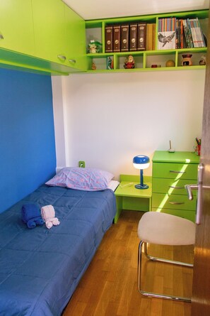 A room with a bed, a desk, a chair, and a bookshelf.