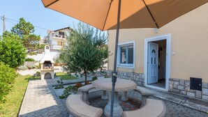 Un patio con un banco de piedra, una pérgola y la entrada de un edificio.