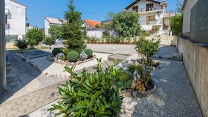 Zona residencial con un patio empedrado, árboles pequeños y un edificio con balcón.
