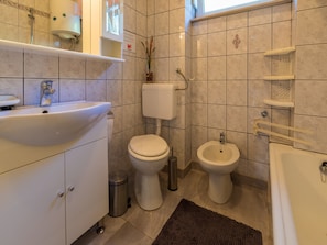 A bathroom with a sink, toilet, bidet, and bathtub.