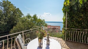A balcony with a round table, a chair, and a potted plant. - Apartments Ljiljana (Dramalj)