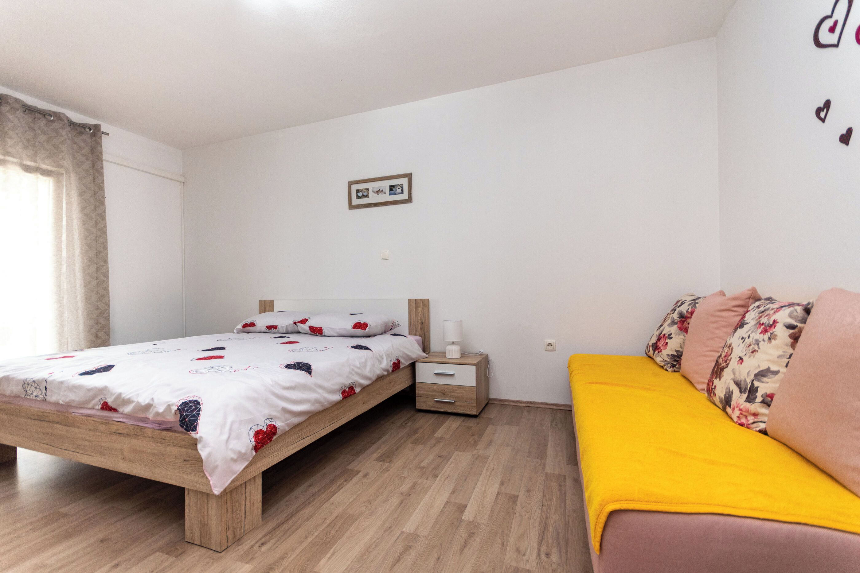 Une chambre à coucher avec un lit en bois, une table de chevet, un canapé et un tableau accroché au mur.