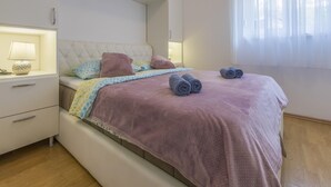 Een slaapkamer met een bed, nachtkastje, lamp en een raam met gordijnen.