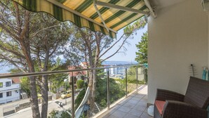 Een balkon met uitzicht op zee, een rieten bank en een betegelde vloer.