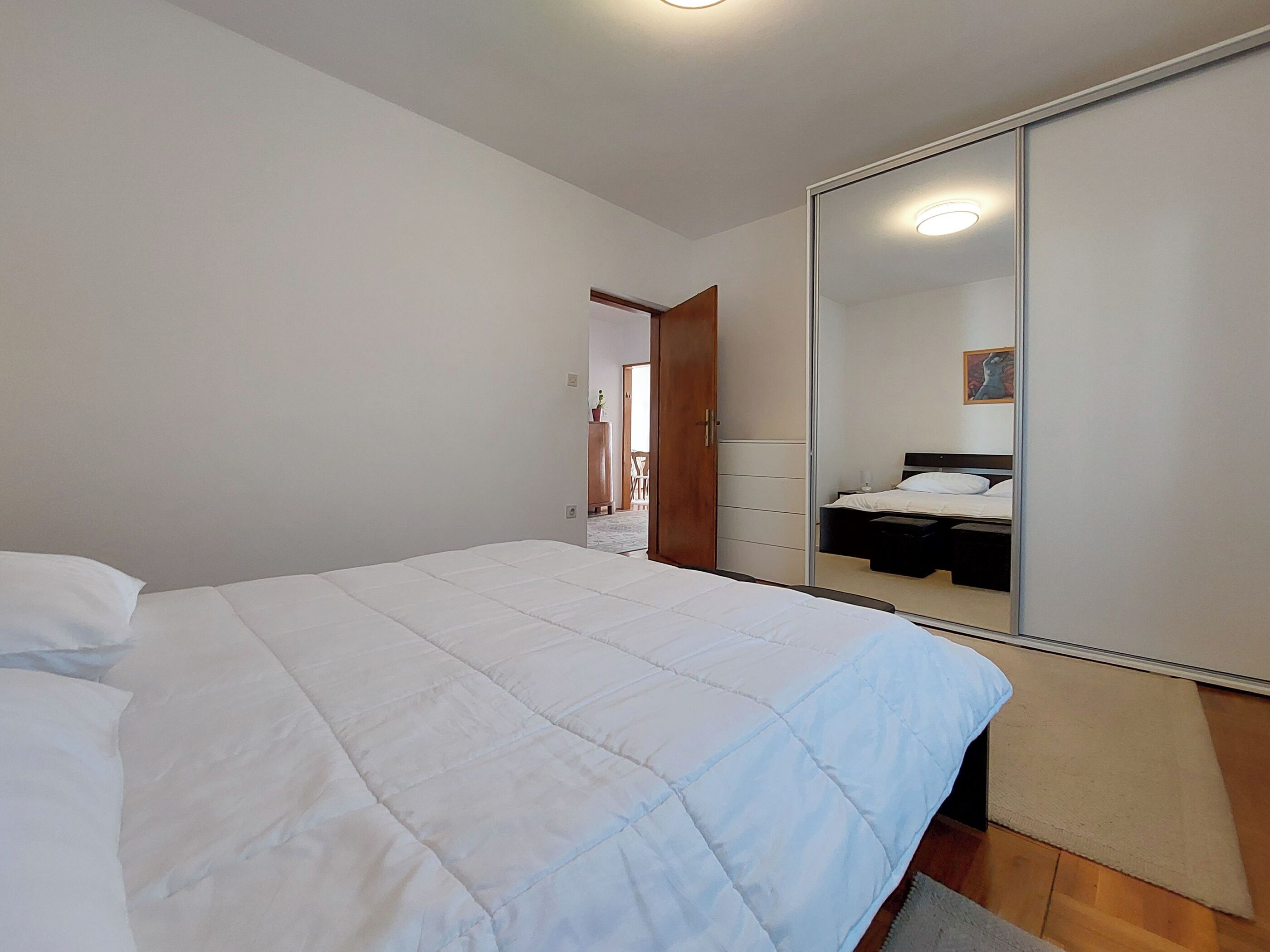 A bedroom with a bed, a wardrobe, and a mirror.