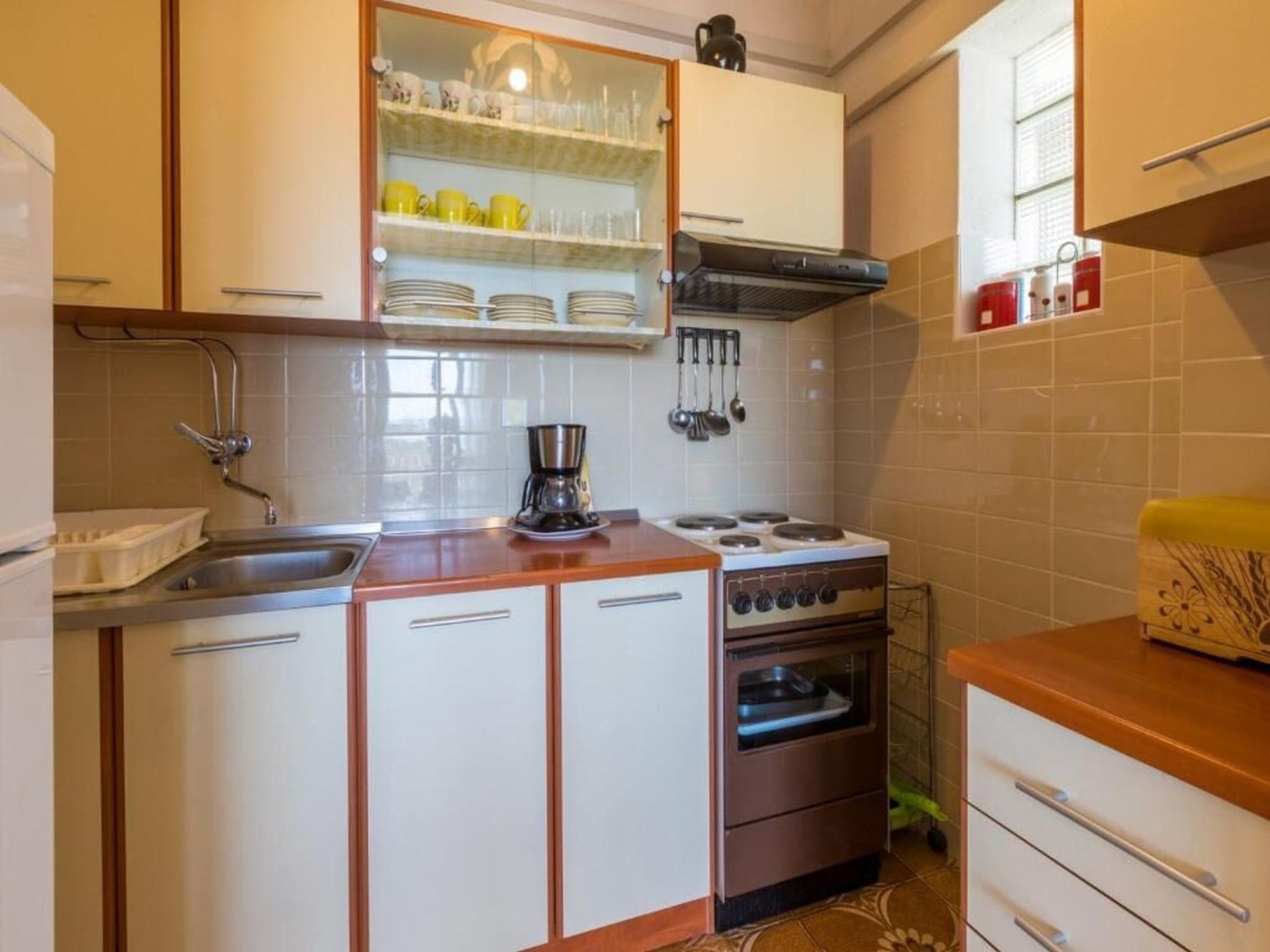 A kitchen with a stove, sink, and cabinets.