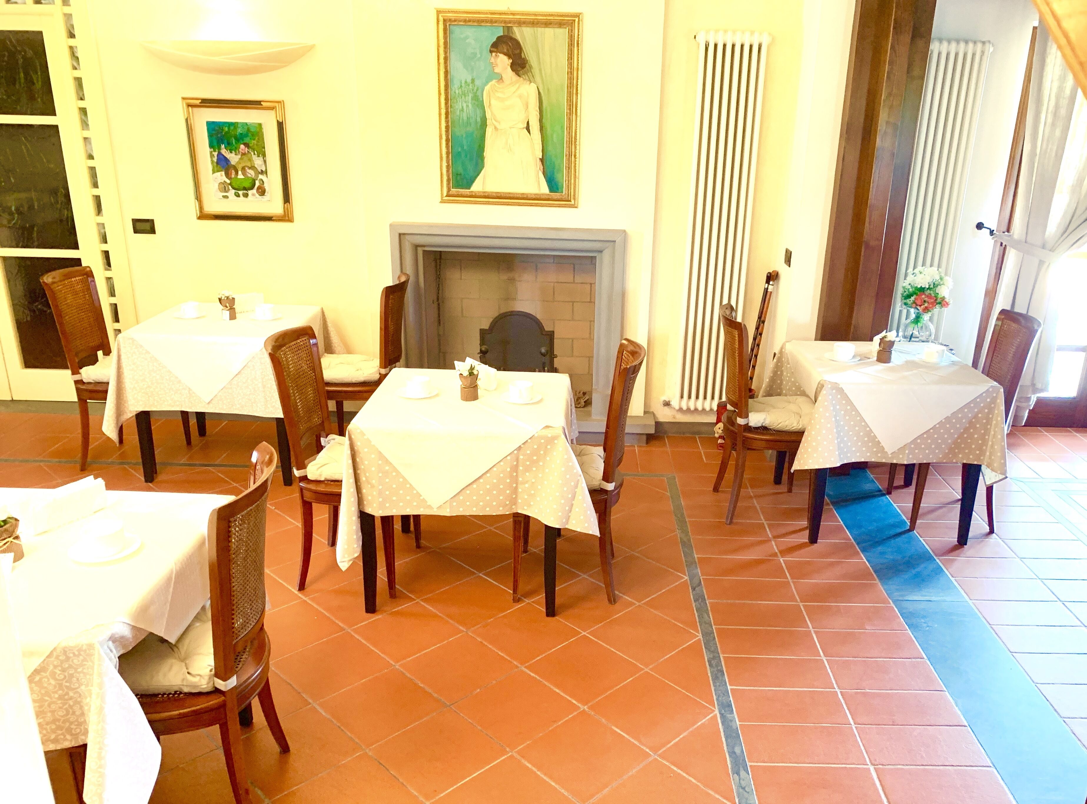A dining area with multiple tables and chairs, a fireplace, and artwork on the walls.