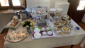 A buffet table with various food items, including fruits, pastries, and beverages, arranged on a table with a white tablecloth. - La Fornace del Sole (Capannori)
