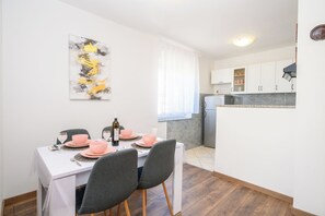 Ein Essbereich mit Tisch für zwei Personen, einer Weinflasche und einem Gemälde an der Wand.