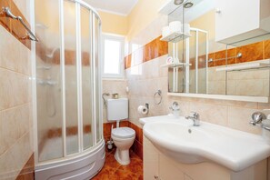 Ein Badezimmer mit Dusche, Toilette, Waschbecken und Spiegel.