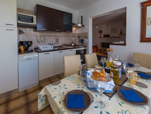 A modern kitchen with a dining area set for a meal. - Apartments Brankica (Crikvenica)