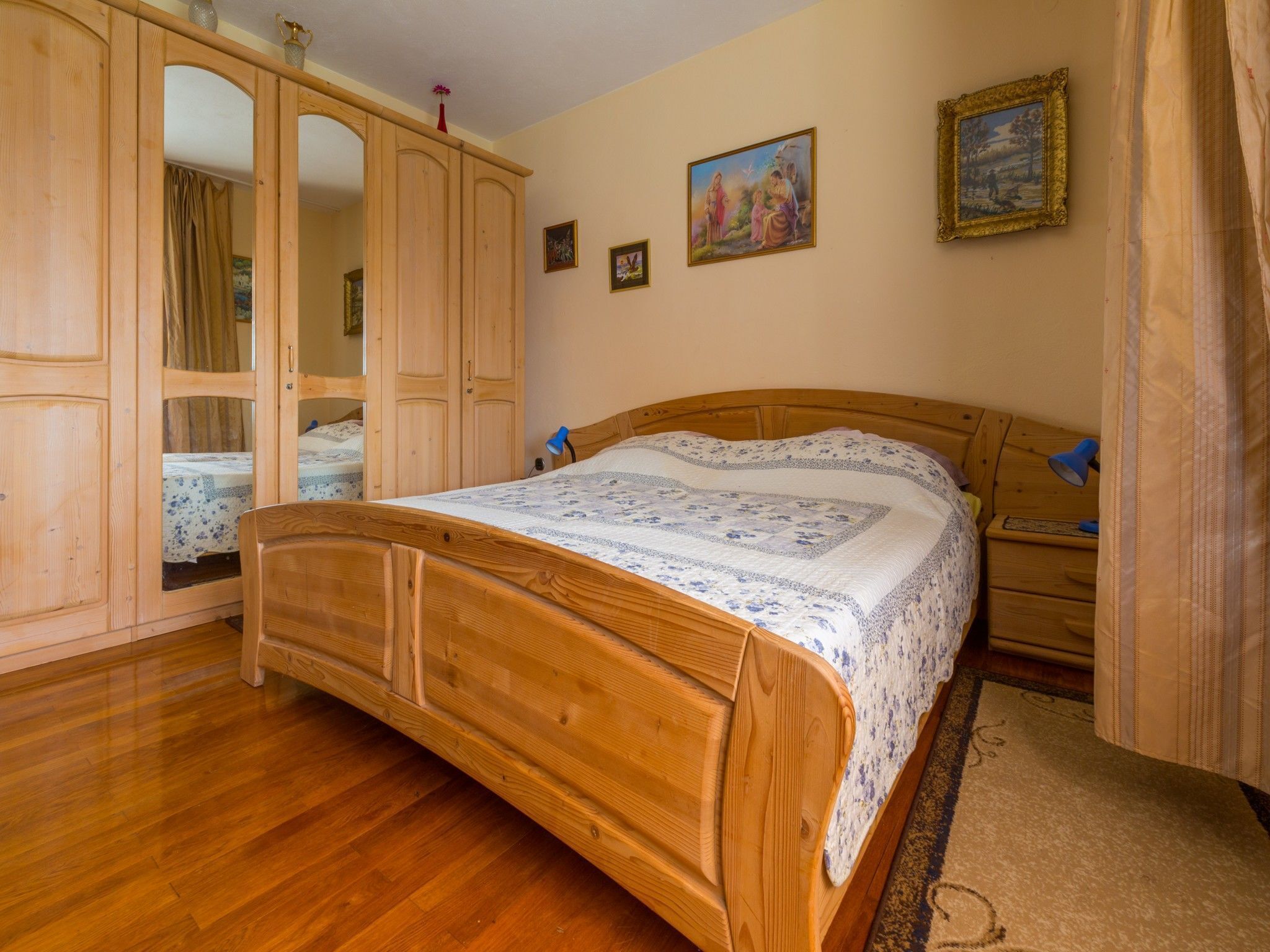 Une chambre à coucher avec un lit en bois, une armoire et une table de chevet.
