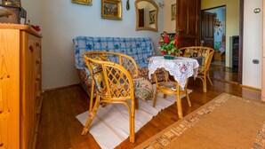 Un coin repas chaleureux avec une table en bois, des chaises en osier, un canapé bleu à motifs et un miroir au mur.