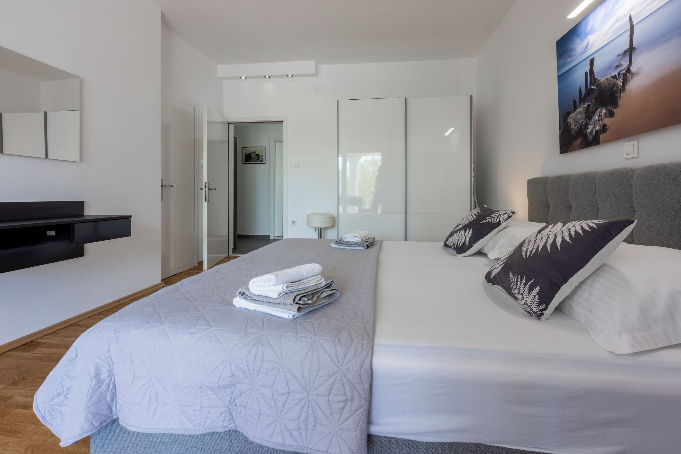 A modern bedroom with a bed, a bedside table, a mirror, and a wardrobe.