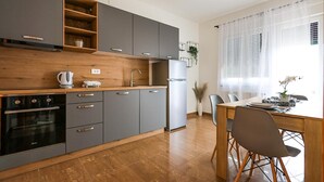Una cucina moderna con mobili grigi, un piano di lavoro in legno e un'area pranzo con tavolo e sedie.