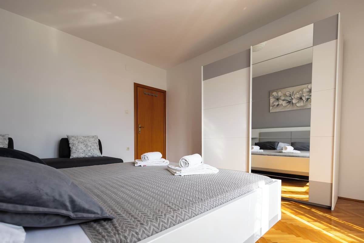 A modern bedroom with a bed, a wardrobe, and a door.