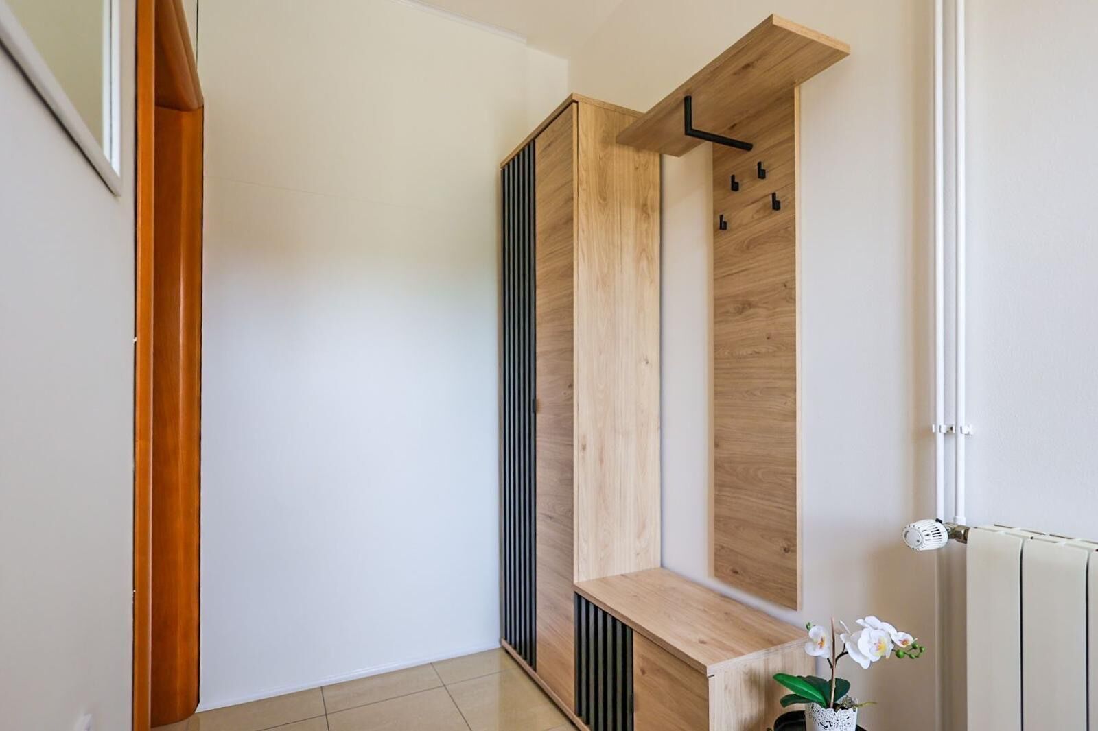 A modern bathroom with a wooden vanity, a radiator, and a small plant.