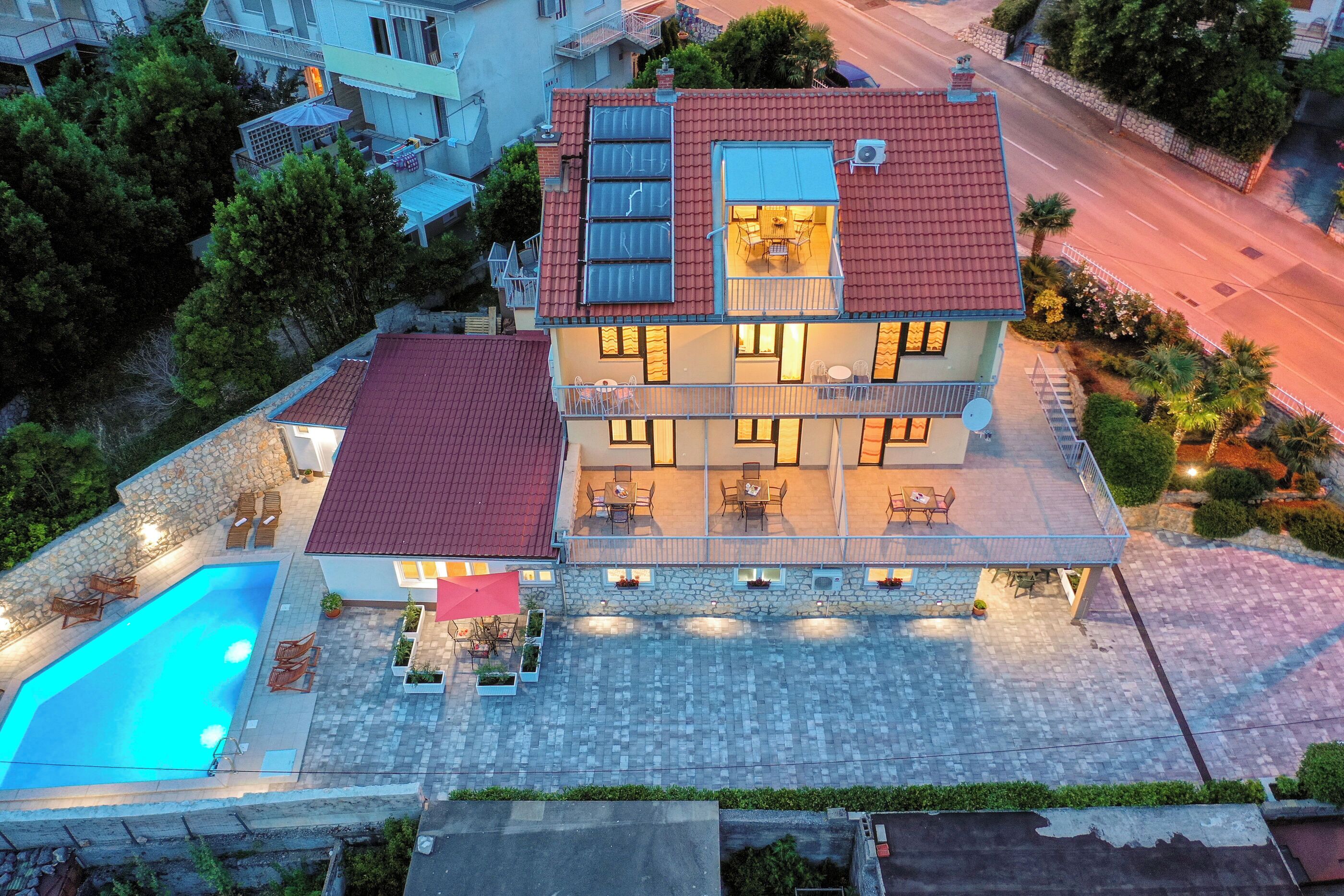 Ein zweistöckiges Haus mit Schwimmbad, Sitzgelegenheiten im Freien und einem Balkon.