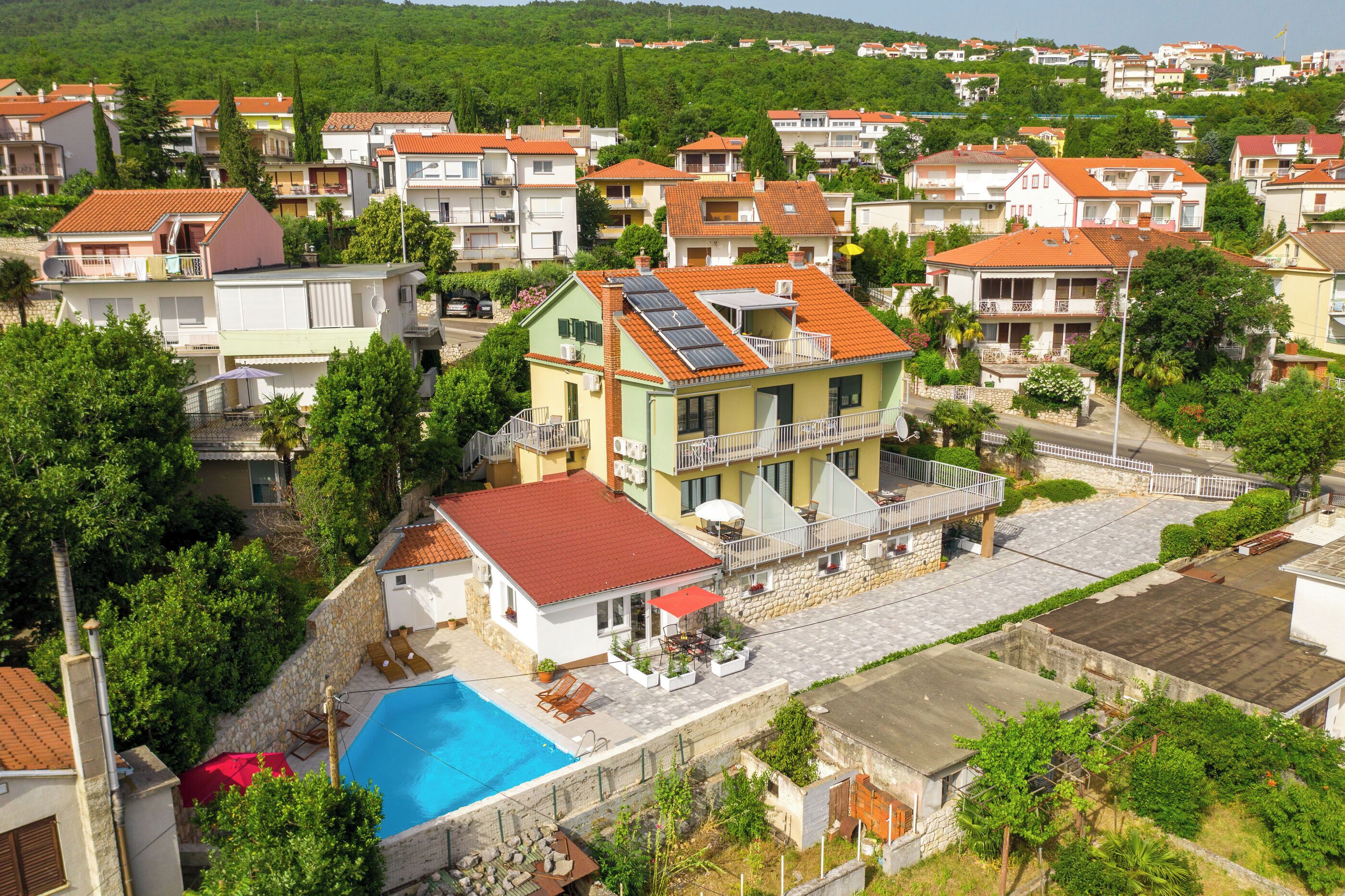A residential area with houses, a swimming pool, and a balcony with solar panels.