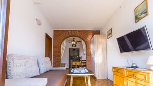 Un salon avec un canapé, une table, un téléviseur et un meuble en bois.