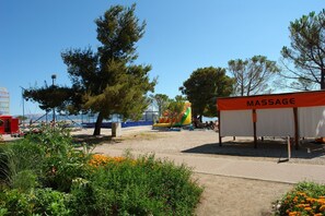 A beachside area with a massage tent, a colorful inflatable slide, and a clear blue sky. - Apartment Dario (Crikvenica)