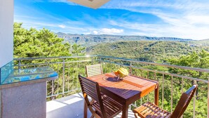 Ένα μπαλκόνι με ένα τραπέζι και καρέκλες, με θέα σε ένα ορεινό τοπίο.