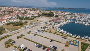 An aerial view of a coastal town with a marina, residential buildings, and a parking area. - Apartment and Room Ilija (Tribunj)