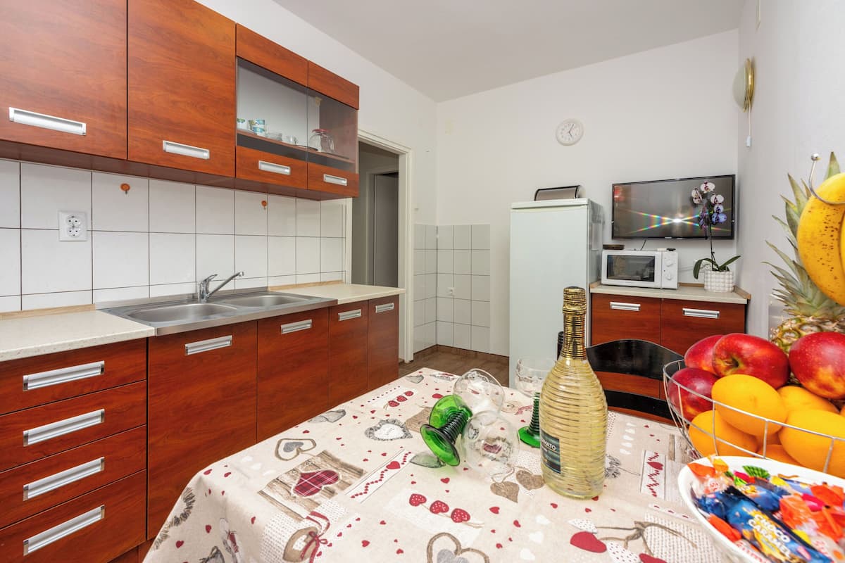 A kitchen with wooden cabinets, a microwave, a TV, and a fruit bowl.