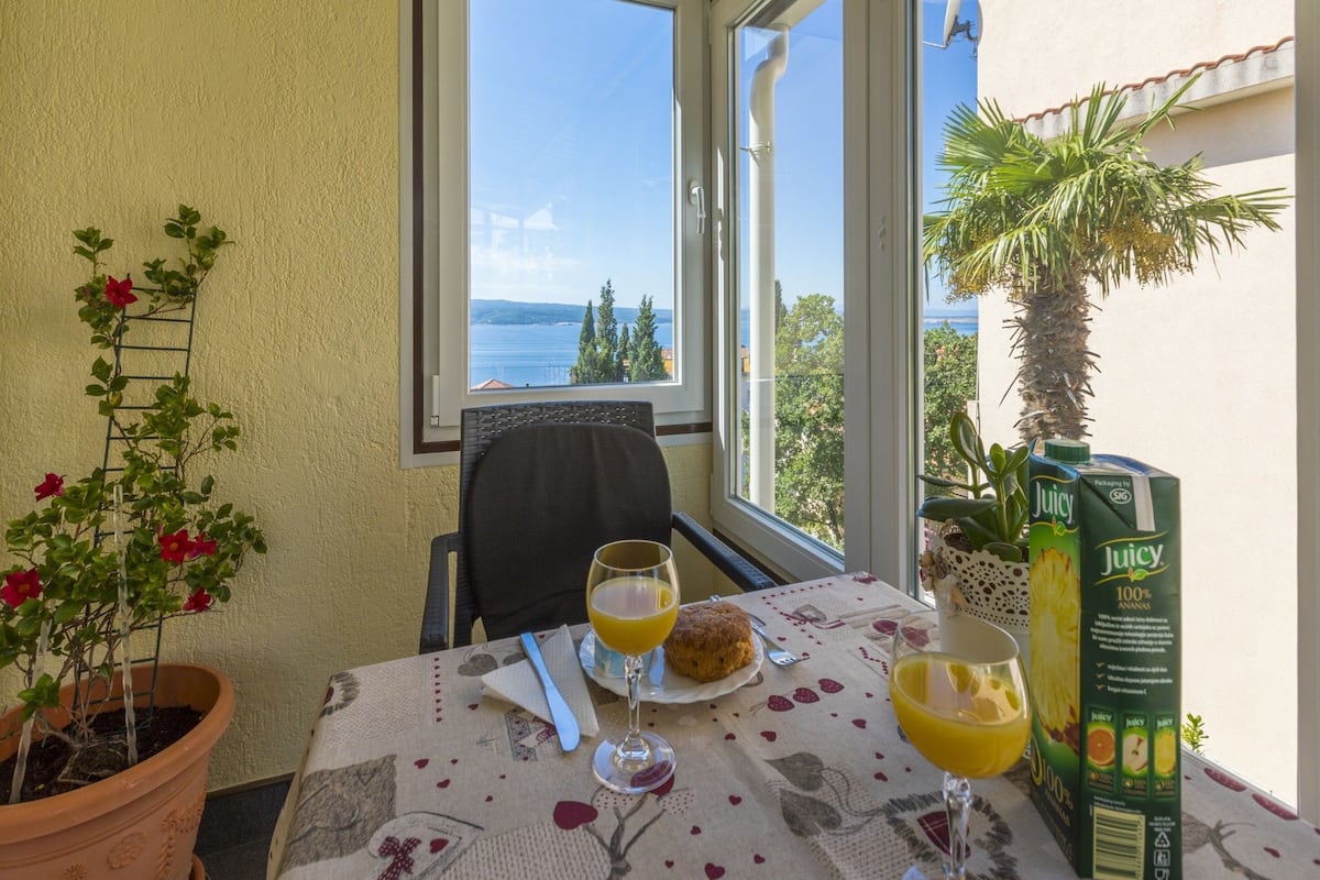 A table with a breakfast setting, including a plate with a pastry, two glasses of orange juice, and a box of juice.