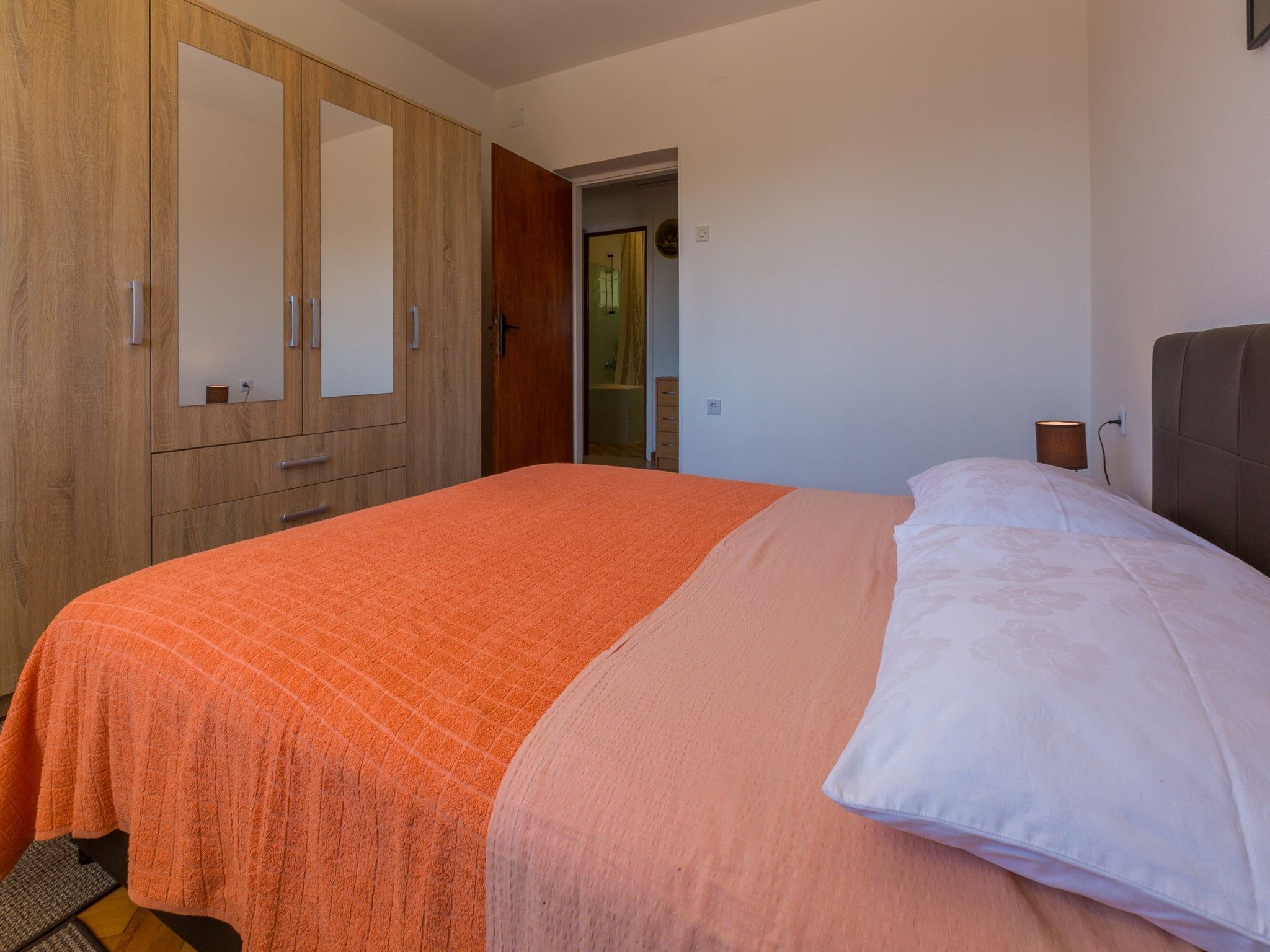 Ein Schlafzimmer mit einem Bett, einem Holzschrank und einer Tür zu einem anderen Raum.