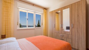 A bedroom with a bed, a wardrobe, and a window with a view. - Apartments Miroslava (Crikvenica)