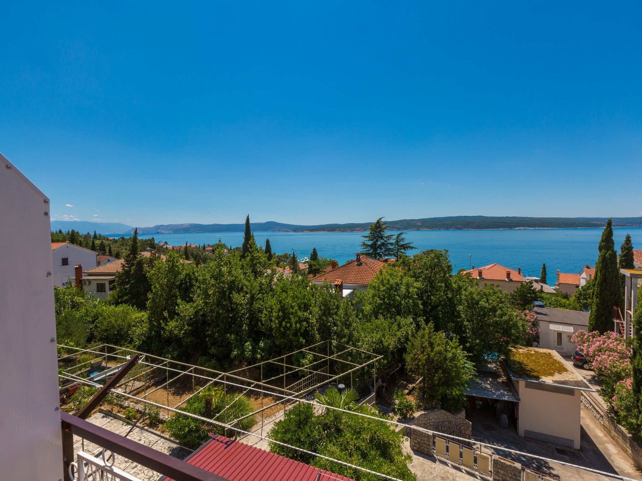 A residential area with a view of a large body of water, likely a lake or sea, and distant mountains.