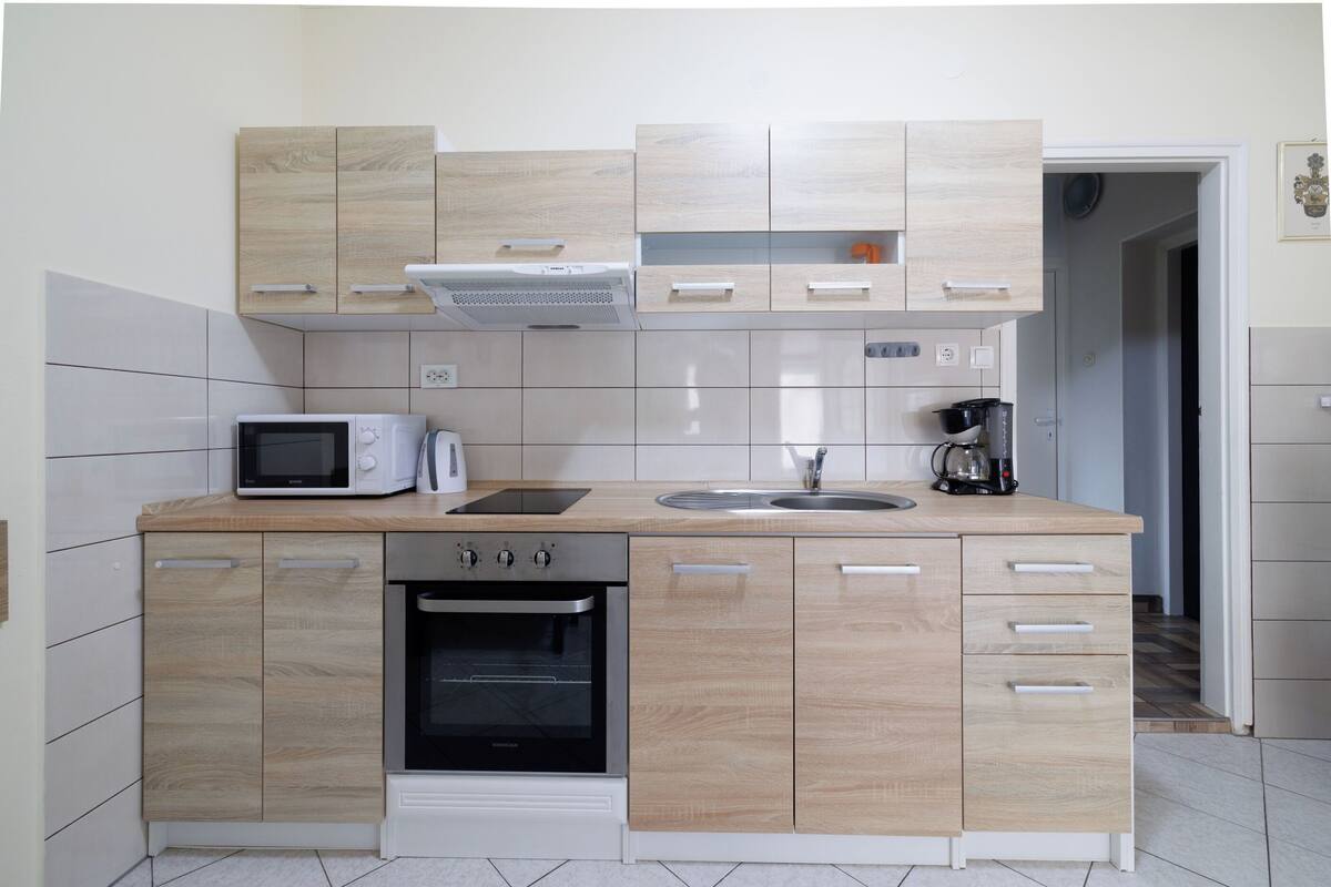 A compact kitchen with a microwave, stove, sink, and wooden cabinets.