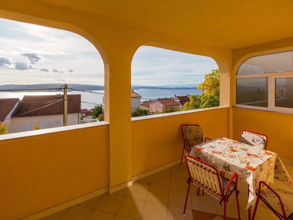 A balcony with a table and chairs, overlooking a body of water and buildings.