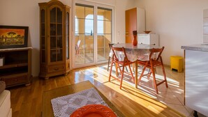 A dining area with a round table and chairs, a wooden cabinet, and a sliding glass door leading to an outdoor space. - Apartments Roko (Crikvenica)