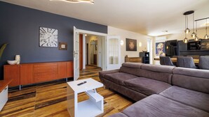 A modern living room with a sectional sofa, a white coffee table, a wooden cabinet, and a dining area with a table and chairs. - Apartments Alin (Dramalj)