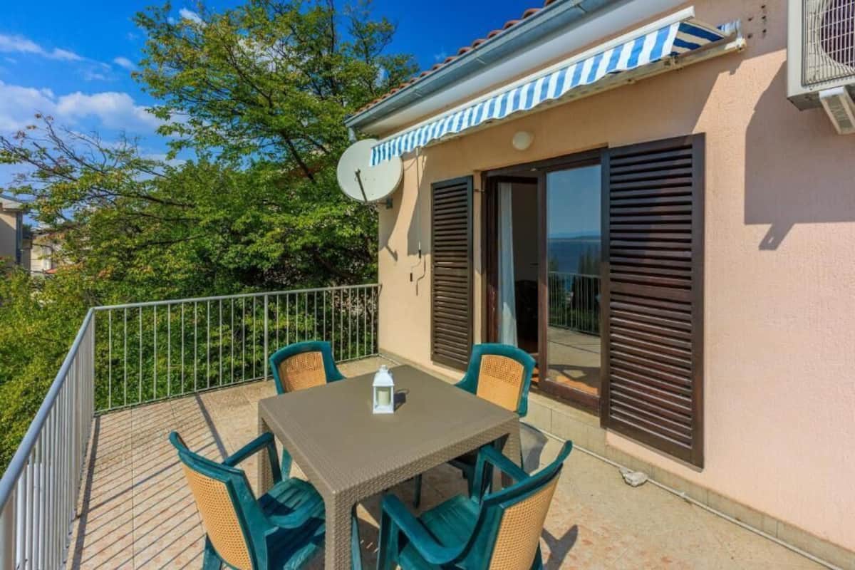 Ein Balkon mit Tisch und Stühlen, einer Satellitenschüssel und einer Schiebeglastür.