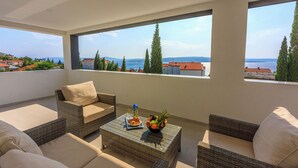 A balcony with wicker furniture, a fruit bowl, and a glass of water. - Apartments Cvetkovic (Crikvenica)