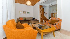 A living room with orange armchairs, a glass coffee table, and a staircase leading to another level. - Apartment Ljubica (Zavalatica)