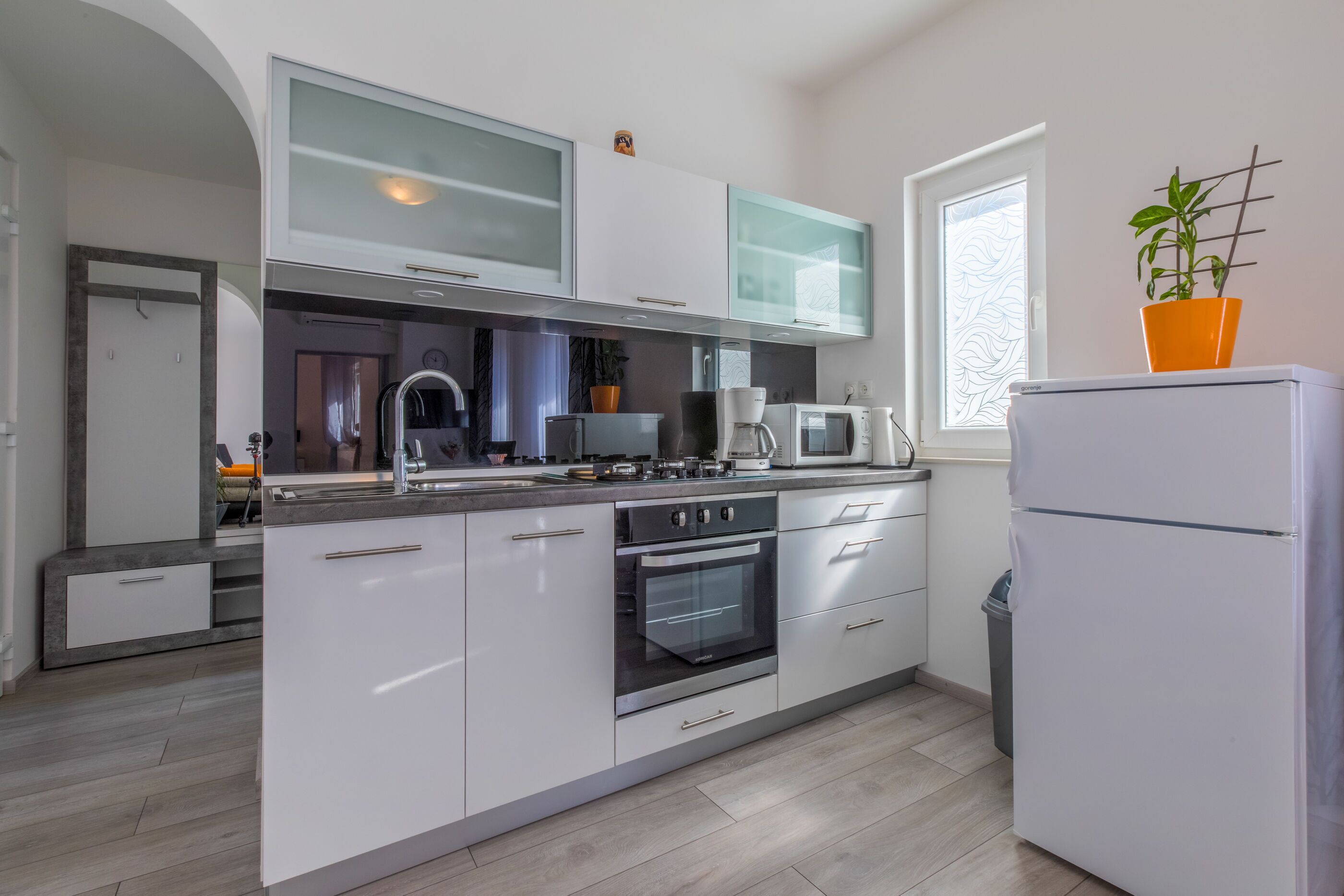 A modern kitchen with white cabinetry, a built-in oven, a microwave, and a refrigerator.