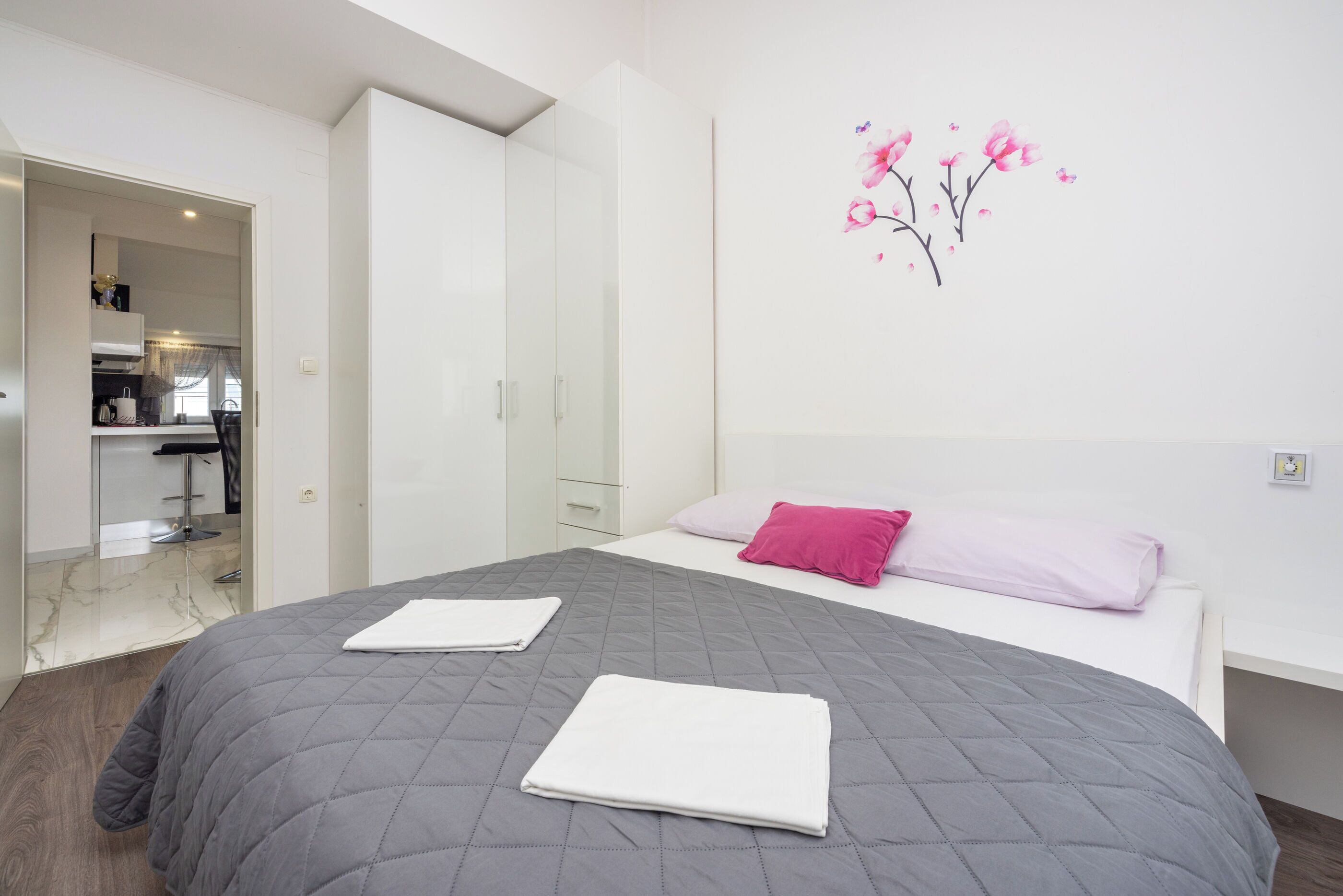 A modern bedroom with a large bed, a wardrobe, and a bathroom visible through an open door.