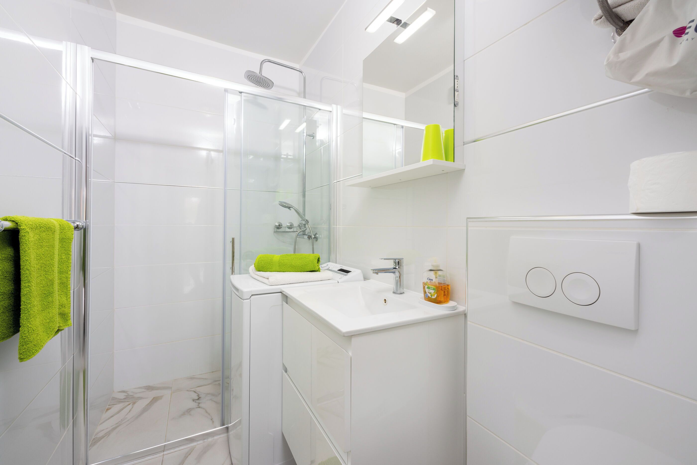A modern bathroom with a glass shower enclosure, a white sink, and a mirror above the sink.