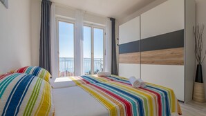 A bedroom with a bed, a wardrobe, and a view of the sea. - Apartment Duda (Novi Vinodolski)