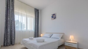 A neatly arranged bedroom with a bed, two bedside tables, and a window with curtains. - Apartment Duda (Novi Vinodolski)