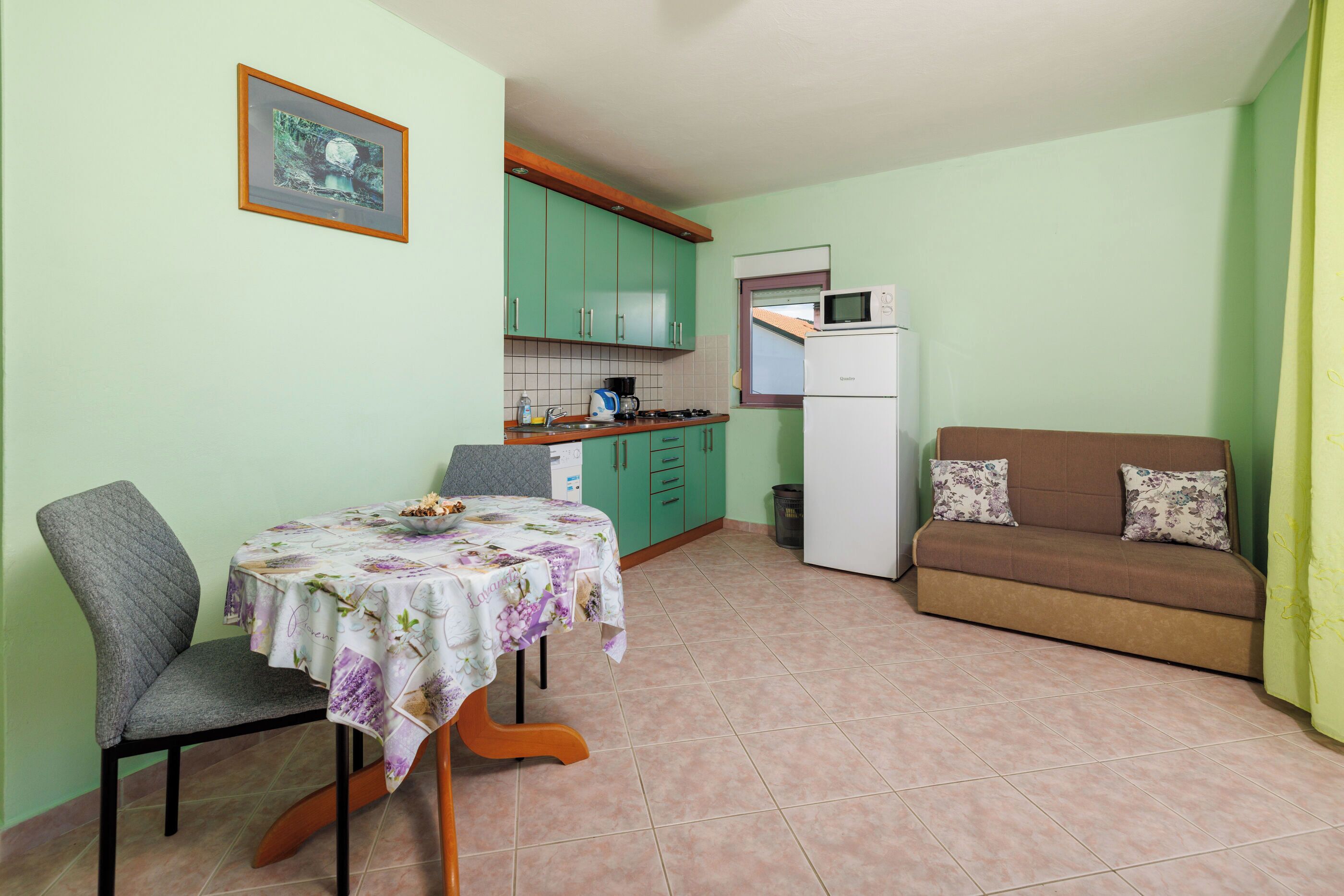 A compact kitchen with a dining table, a sofa, and a microwave.