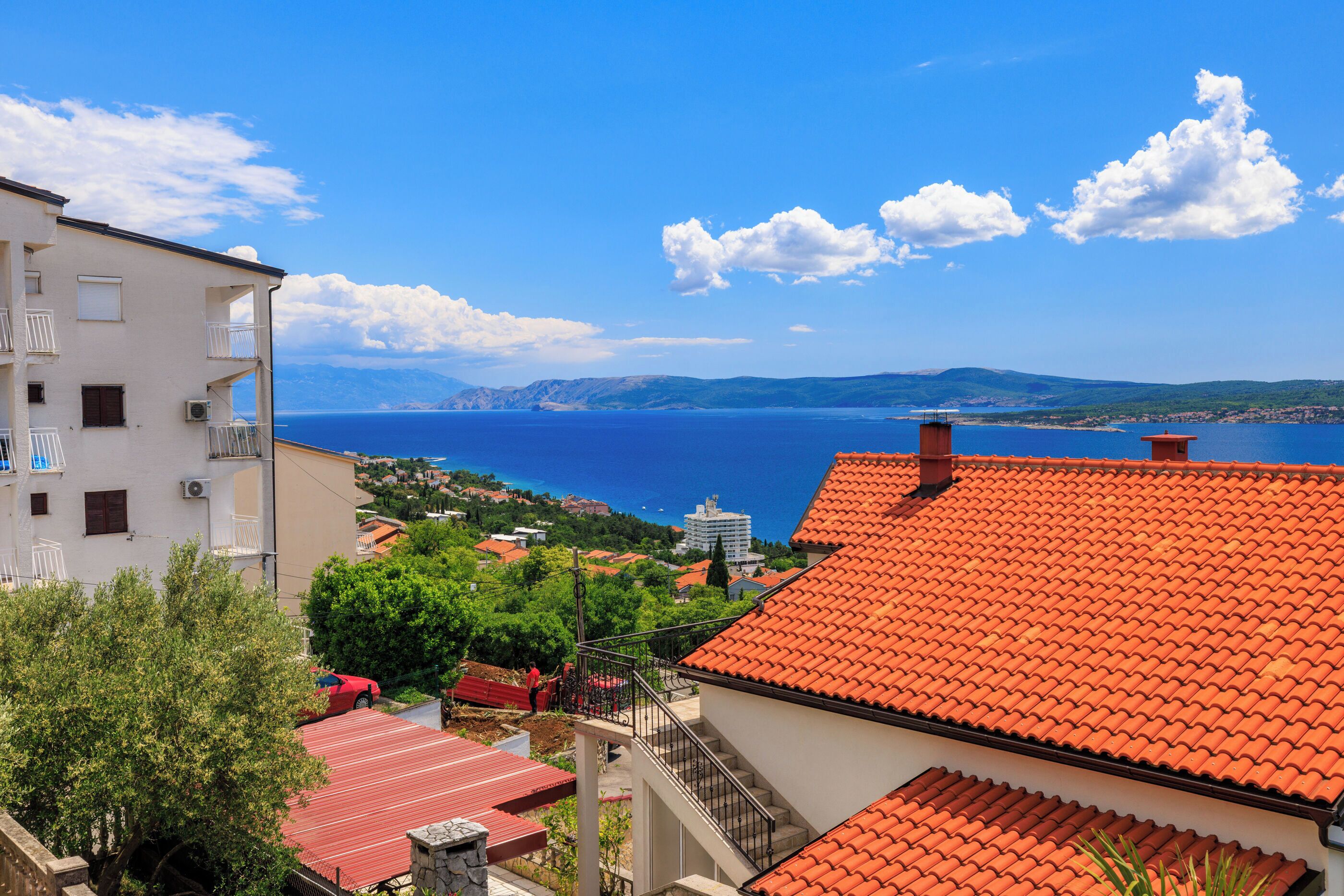 A coastal town with buildings, a red-roofed house, and a view of the sea.