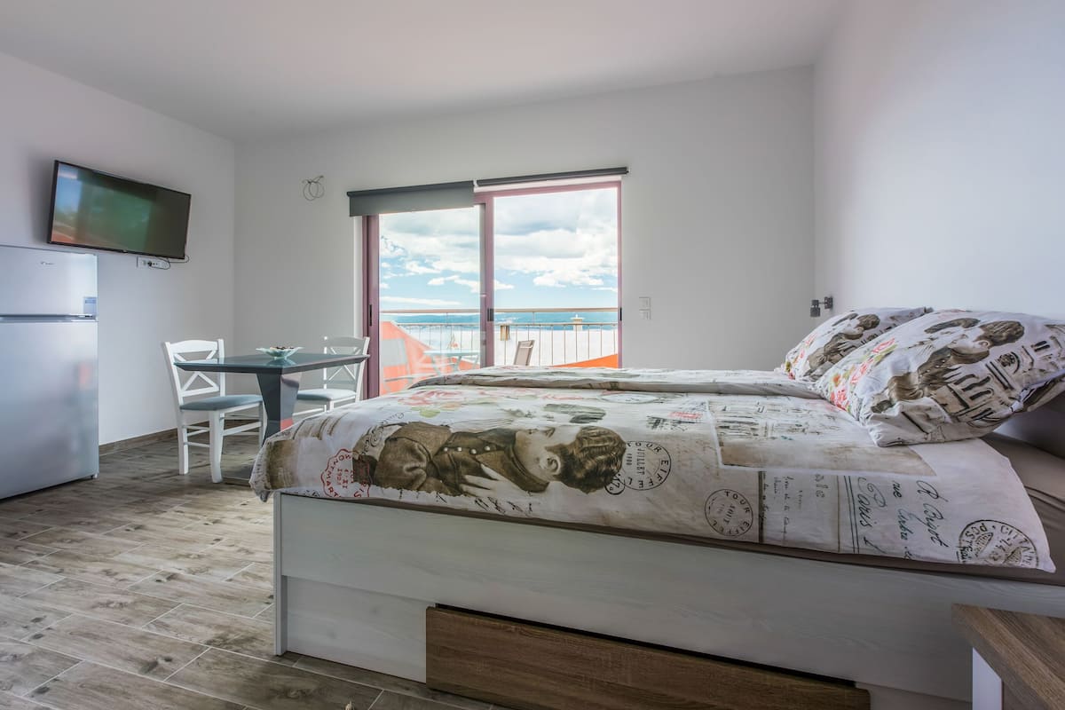 Une chambre avec un lit, une télévision, un bureau et un balcon donnant sur la mer.